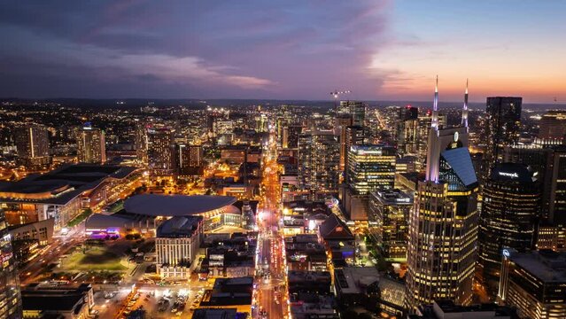 Night hyperlapse of traffic in Nashville's downtown streets captured from above during dusk. Fly Through aerial shot of buildings, showcasing metropolis bustling nightlife and modern architecture