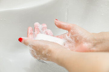 woman washing her hands with soap in the bathroom. man washes his hands with soap. 