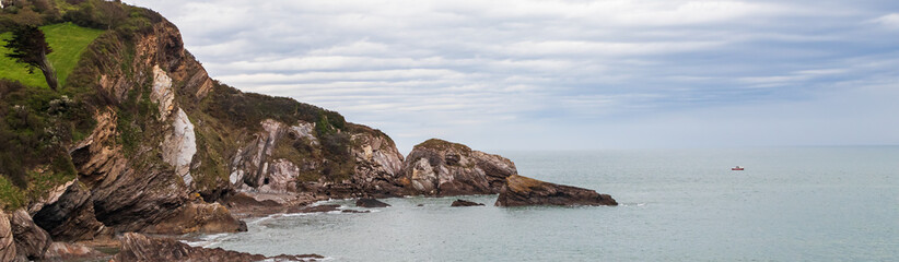 Obraz premium Seascape with a rocky shore. Wide panoramic view, banner with rocky sea coast landscape and cloudy sky