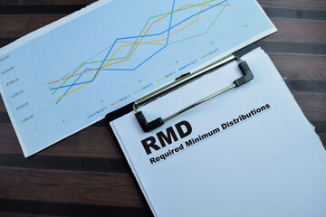 Concept of RMD - Required Minimum Distributions write on paperwork isolated on wooden background.