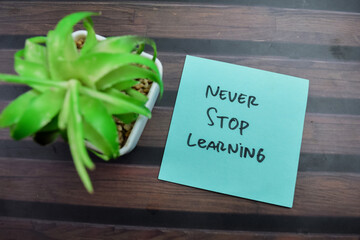 Concept of Never Stop Learning write on sticky notes isolated on Wooden Table.
