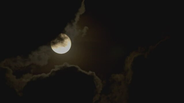 Full moon in the night sky with clouds flying across it