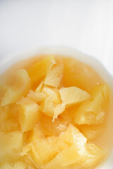 Canned pineapples in a white cup. Chopped pineapples.