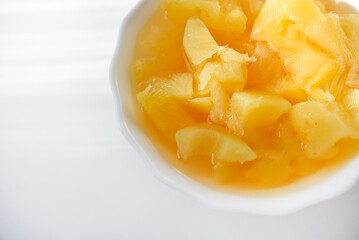 Canned pineapples in a white cup. Chopped pineapples.