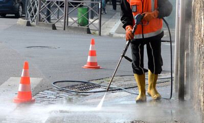 un travailleur nettoyant une rue à haute pression