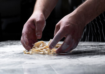 Cooking pasta spaghetti dough with flour on a dark black background with spatial area. Food banner,...