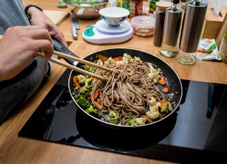 Chef at the kitchen preparing japanese buckwheat pasta with lentils