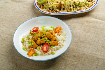 Thai chicken with rice in sauce, and salad with kiwi on the table