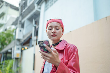 Fototapeta premium Traveler Gen z girl leather fashion with punk Asian woman tourist&nbsp;in city street searching location in map application online smart phone using GPS&nbsp;navigating