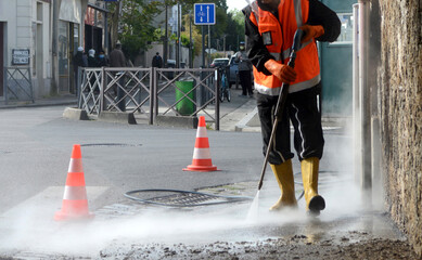 un travailleur nettoyant une rue à haute pression