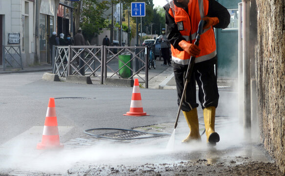 un travailleur nettoyant une rue &agrave; haute pression