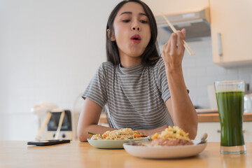 Asian Girl  eating Thai food in kitchen counter Home delivery food feeling happy 