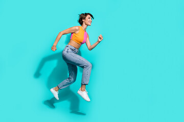 Full length photo of hurrying excited woman wear pink orange top jumping high running fast empty space isolated teal color background