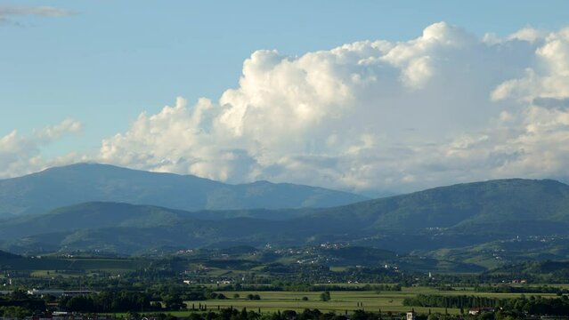 breve timelapse con vista dettagliata su una piccola parte del territorio naturale tra la pianura e la montagna nel nord est Italia, in estate, mentre le nuvole lontane si muovono sopra le montagne