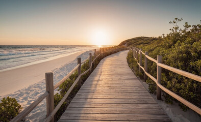 Obraz premium Long Boardwalk to White Sand Beach and Ocean at Sunset with Shrubs on Sides