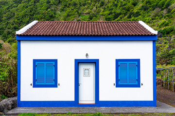 Beautiful white house with blue door frames and windows typical of Fajã dos Cavales. São Jorge...
