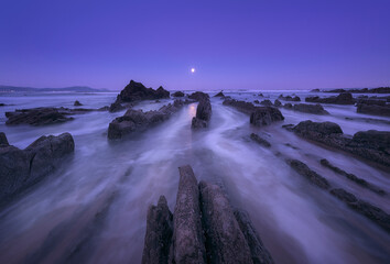 unar sunset on Barrika beach, Bizkaia, with the sea water running between the flysch