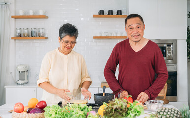 A man and woman are standing in a kitchen preparing food