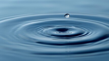  A tight shot of a water droplet atop tranquil water, surrounded by a blue expanse of sky, with the droplets' reflection mirrored beneath