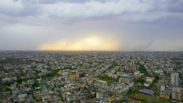 flying backward aerial drone shot showing densely populated buildings houses offices cityscape of jaipur with sunrise and monsoon clouds overhead showing this serene peaceful city