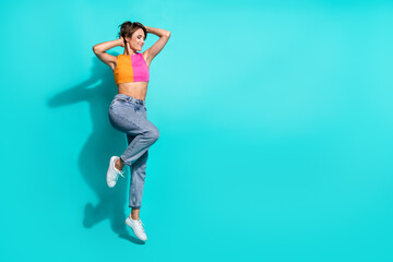 Obraz premium Full length photo of positive pretty woman wear pink orange top jumping high empty space isolated teal color background