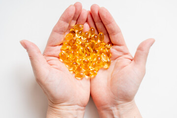 A lot of pills of bright yellow color with fish oil in women's palms. Omega 3 as a drug for weight loss and rejuvenation.