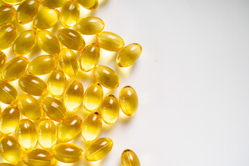 Lots of omega-3 fish oil tablets, bright yellow on a white background. Copy space, banner.