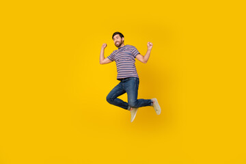 Full length body photo of young adult bearded man jumping raised hands up enjoying freedom isolated over yellow color background