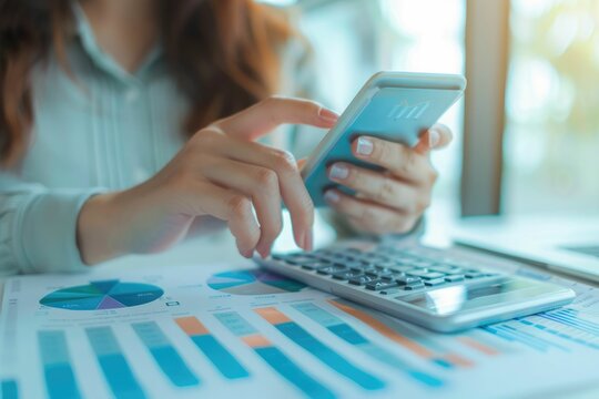 hand of business woman hold smartphone use analyzing and calculating the annual income and expenses, a financial chart and financial report, technology and bussiness concept.