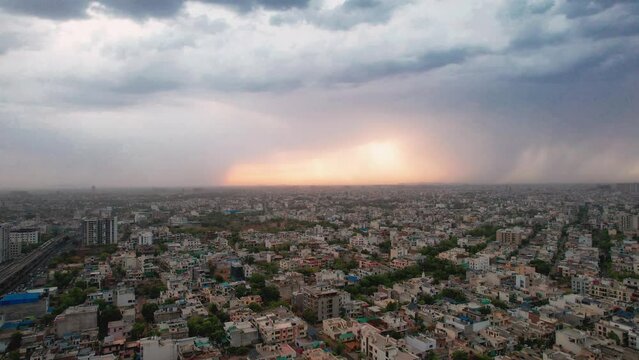 forward aerial drone shot showing densely populated buildings houses offices cityscape of jaipur with monsoon clouds and golden sunset