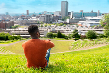 Man Sitting on a Hilltop Overlooking  Cityscape