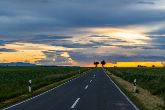 Sonnenuntergang mit langer gerader Landstra&szlig;e