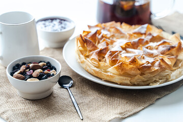 Homemade pastries, apple pie made of filet dough, nuts and tea on a white table. Selected focus.
