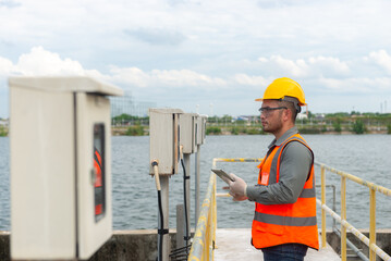 an engineer looking at the valve gauge plumbing system and type it down on a tablet to check the gauge at standard value, waste water treatment, tablet controller system