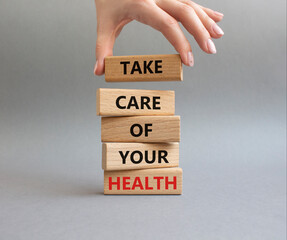 Health symbol. Wooden blocks with words Take Care of your Health. Doctor hand. Beautiful grey background. Health concept. Copy space.