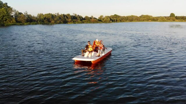 family with children on a pedal boat ride on a lake at sunset