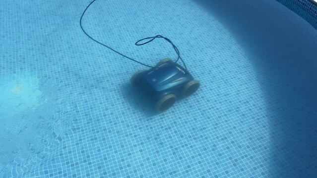 An automatic pool cleaner operating underwater in a clear blue swimming pool. Top view