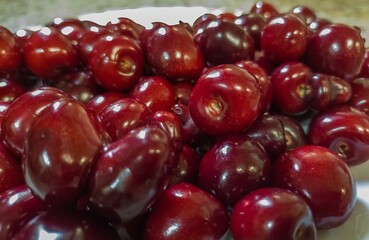 the first harvest of dark red cherry fruits grown in the gardens of the South of Russia, close-up