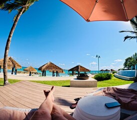 A person sitting on a lounge chair under an umbrella at The Royal Bahamian Sandals Resort