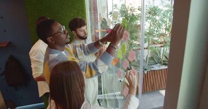 Business team using a glass wall as dynamic tool for engagement, transforming the workplace into a hub of creativity and analysis.