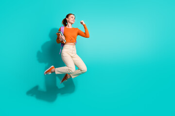Full length photo of smart woman wear orange crop top hold rucksack copybooks look empty space isolated on turquoise color background