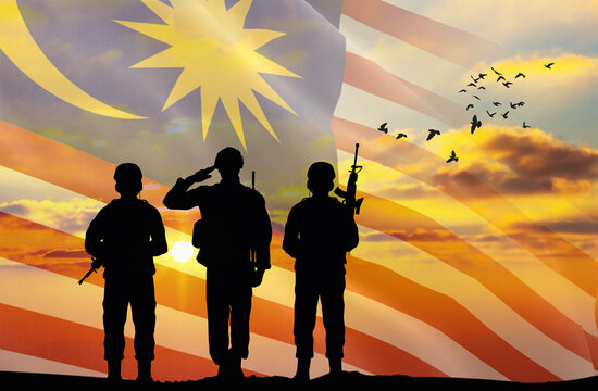 Silhouettes of soldiers with a background of the Malaysia flag and a sunset or sunrise. Concept of national holidays. Commemoration Day.
