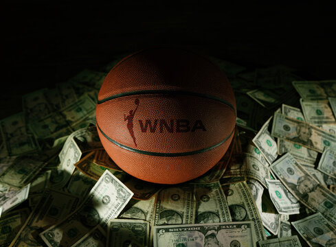 Raleigh, NC - USA - 04-15-2024: Basketball with WNBA text and logo on a pile of money