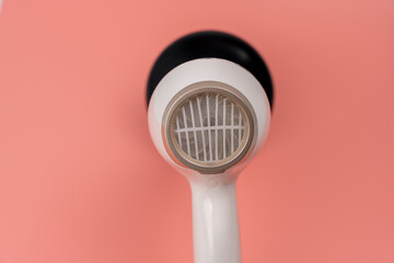 Hair dryer for drying hair on a pink background. The buttons are labeled 