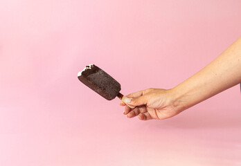 female hand holds a bitten popsicle, ice cream on a stick