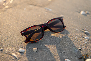 sunglasses lie on the sand on the beach at sunset