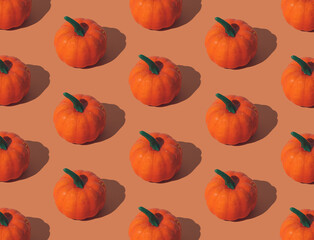 Trendy autumn or fall pattern made with orange pumpkins on orange background. Minimal autumn composition. Nature flat lay. Season concept. Pumpkin aesthetic.