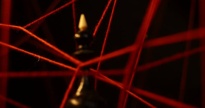 Among the taut red threads hangs a black queen chess piece. Psychology and psychiatry. Visualization of phobias and their removal