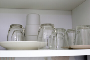 Clean dishes and tableware on a white shelf