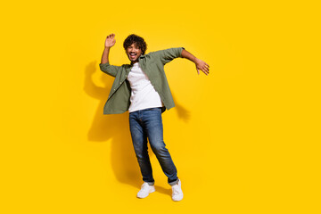 Fototapeta premium Portrait photo of young funny mexican guy in khaki shirt dancing boogie woogie at hipster party isolated on yellow color background